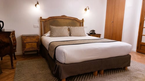 Chambre de l'Hôtel Dandy Rouen avec tête de lit ornée, literie blanche, tables de nuit en bois et décor classique
