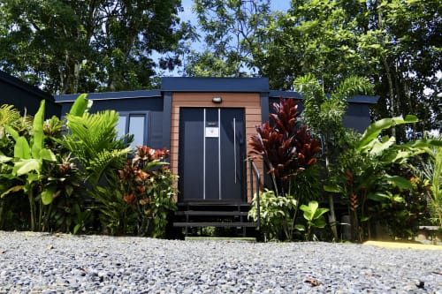 Villa moderna del Contenedores Boutique Hotel Costa Rica con fachada oscura, vista al jardín tropical y exuberante vegetación