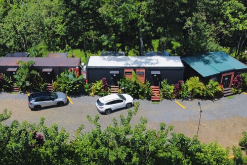 Vista aérea del Contenedores Boutique Hotel en Costa Rica con edificios de contenedores modernos, autos estacionados, jardines exuberantes y