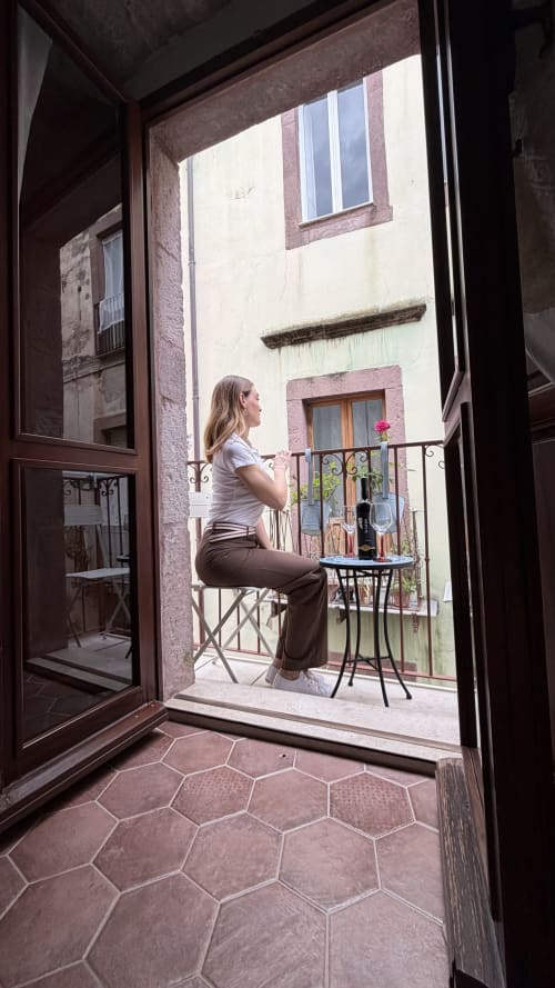 Donna che si rilassa sul balcone di Regnos Altos Boutique Rooms a Bosa, Italia, con vista sull'architettura storica