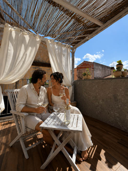 Coppia che assapora vino sulla terrazza privata di Regnos Altos Boutique Rooms a Bosa, Italia