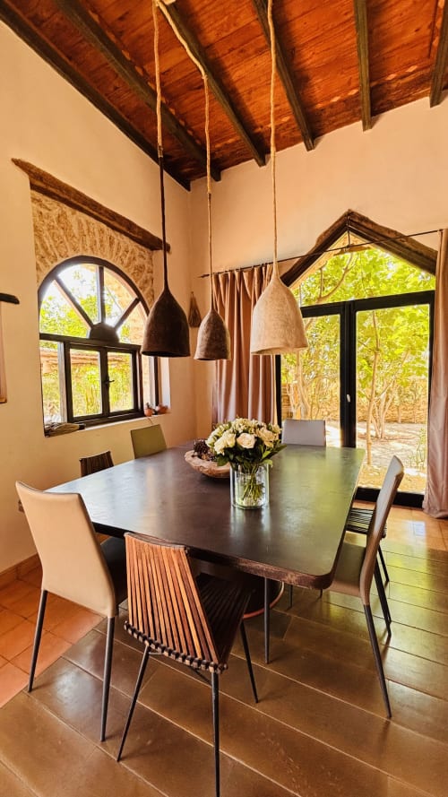Dining room at Maison la Chèvre, Essaouira with pendant lights, dark table, and arched window views