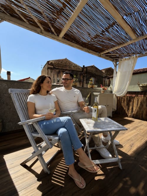 Coppia che assapora vino sulla terrazza privata di Regnos Altos Boutique Rooms a Bosa, Italia