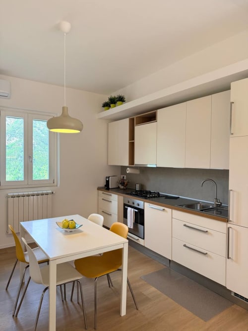 Modern kitchen and dining area in Blues room at Adagio Ravello with cream cabinetry, dining table, and garden view windows