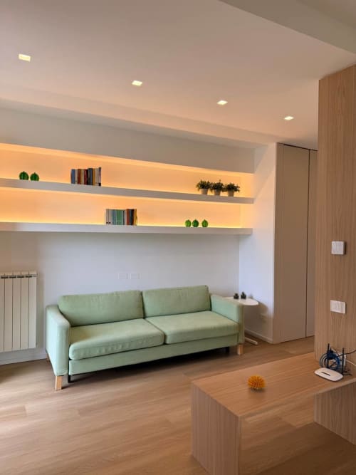 Modern living room at Adagio Ravello with green sofa, illuminated floating shelves, wooden furniture, and garden views