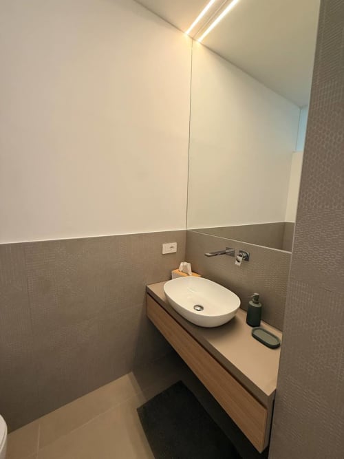 Modern bathroom in Blues room at Adagio Ravello with white oval sink, wooden vanity, and tiled walls