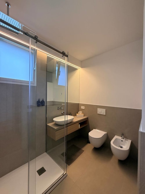 Modern bathroom in Adagio Ravello's Blues room with walk-in shower, vessel sink, bidet, and warm earth-tone finishes
