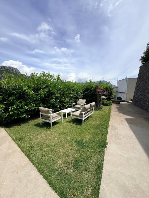 Adagio Ravello garden terrace with lounge chairs, manicured lawn, green hedges, and mountain views under blue sky