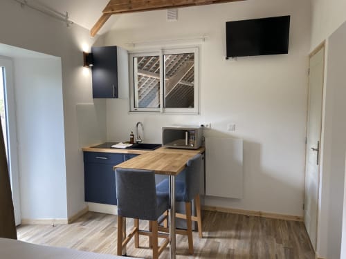 Studio confort kitchenette with dining table at Domaine des Piéris, Grandcamp-Maisy. Modern beamed cottage interior with