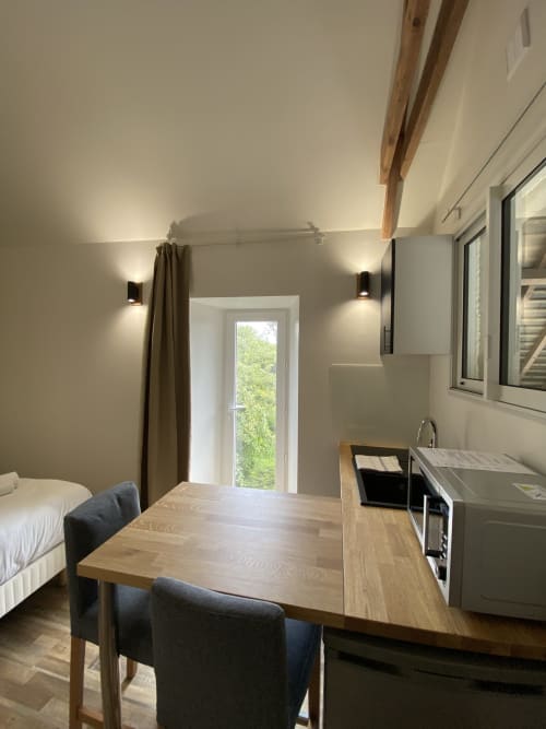 Modern studio cottage at Domaine des Piéris with dining table, kitchenette, bed, and garden view door