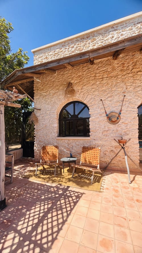 Sunny patio at Maison la Chèvre guesthouse in Essaouira with stone walls, woven chairs, and rustic decor