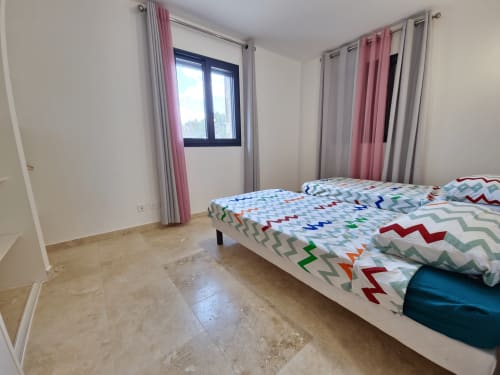 Bright bedroom with two beds and colorful bedding at Smooth Luberon apartment in Villars, mountain view window