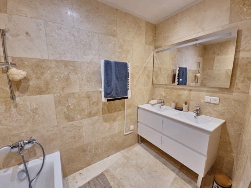 Modern bathroom at Smooth Luberon with marble tiles, white vanity, walk-in shower, and mirror in Villars apartment