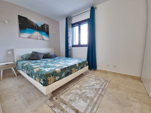 Modern bedroom at Smooth Luberon in Villars with white bed, teal accents, mountain view artwork, and blue curtains
