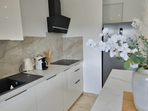 Modern white kitchen with marble backsplash at Smooth Luberon, Villars apartment with black cooktop and white flowers