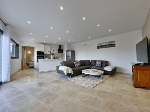 Modern open-plan living area at Apt Belvedere in Villars with black sectional sofa, kitchen, and recessed ceiling lights
