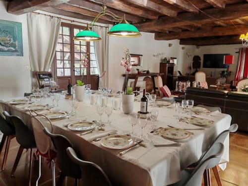 Elegantes Esszimmer im Domaine De Millox mit langem weißem Tisch, formaler Tischdeckung und grünen Pendelleuchten