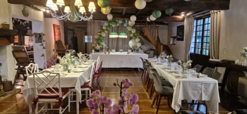 Elegant dining hall at Domaine De Millox with white tablecloth tables, decorative green and white hanging spheres, and purple