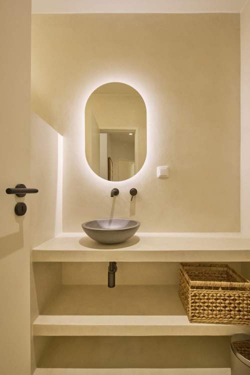 Modern minimalist bathroom at Casa Redonda in Aroeira with illuminated oval mirror, vessel sink, and floating vanity