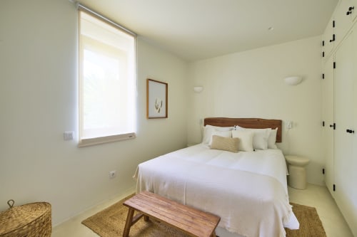 Bright bedroom at Casa Redonda in Aroeira with wooden bed, garden view window, and modern amenities