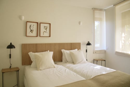 Bright bedroom in Casa Redonda apartment at Aroeira with cream bedding, wooden headboard, and garden views through windows