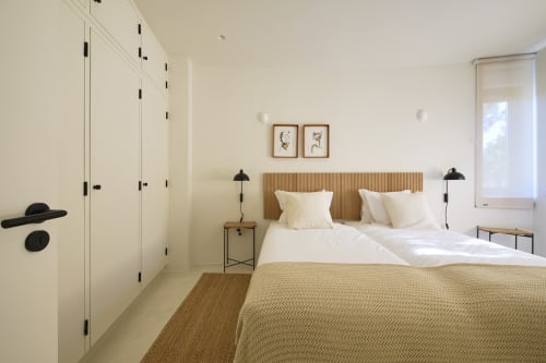 Bright bedroom at Casa Redonda by Villas Aura in Aroeira with wooden headboard, cream bedding, wardrobe, and garden view