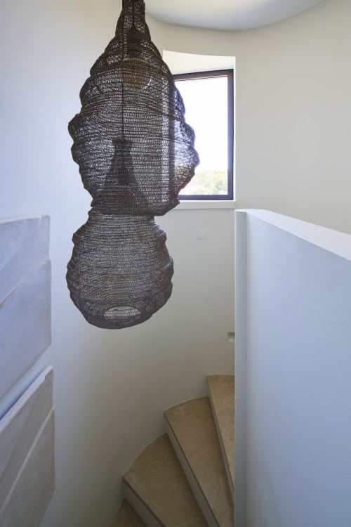 Dark mesh pendant light hanging in stairwell at Casa Redonda, Aroeira Portugal apartment