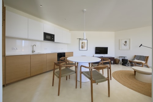 Modern open-plan living area at Casa Redonda, Aroeira with dining table, wooden chairs, kitchen, and living space
