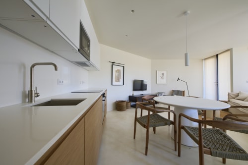 Modern open-plan kitchen and dining area in Casa Redonda apartment at Aroeira villa, featuring wooden furnishings and garden