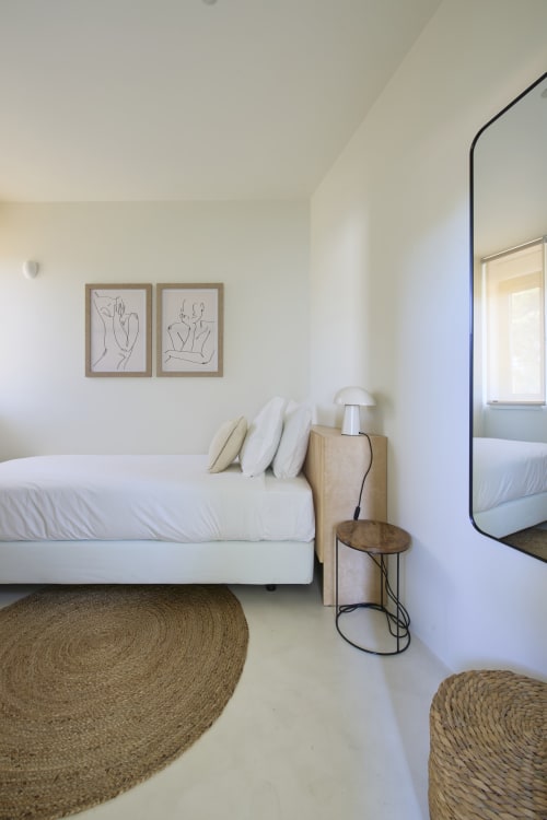 Modern bedroom in Casa Redonda, Aroeira - white bed with pillows, line art, natural rugs, and minimalist design
