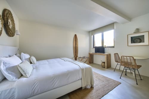 Bright studio bedroom at Casa Redonda in Aroeira with white bed, wooden desk, rattan chairs, and garden view