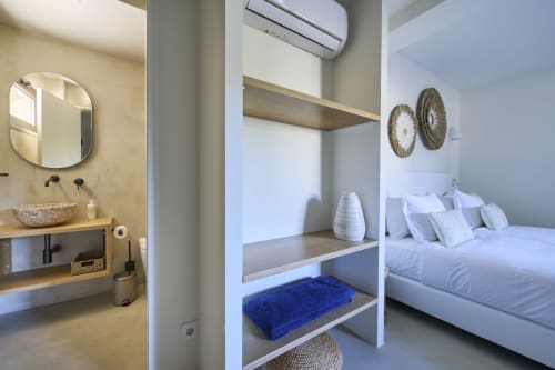 Modern studio apartment at Casa Redonda showing bathroom, bedroom with white linens, and built-in shelving in Aroeira