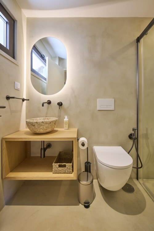 Modern bathroom at Casa Redonda Studio, Aroeira with stone sink, illuminated mirror, and contemporary fixtures