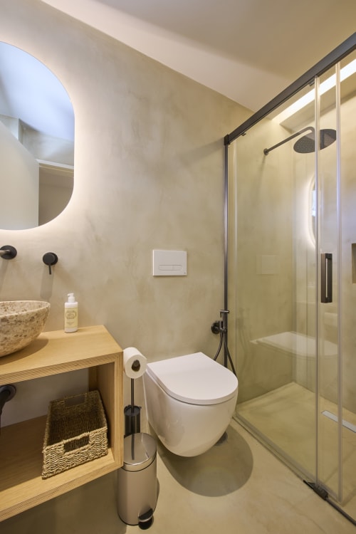 Modern bathroom at Casa Redonda Studio, Aroeira with rainfall shower, illuminated mirror, wooden vanity and neutral tones