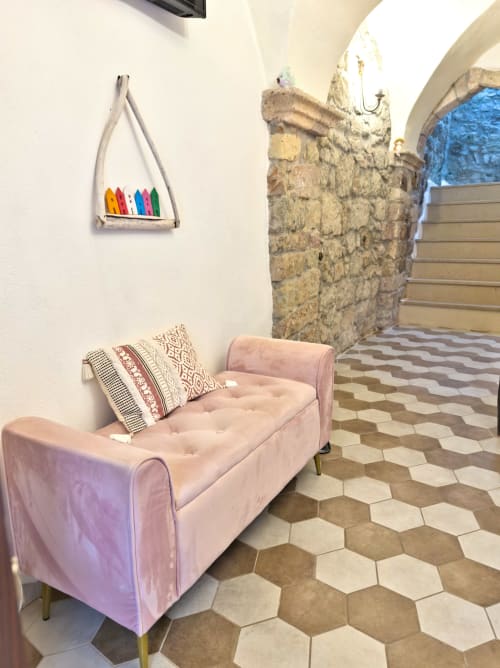 Panchetta rivestita in rosa con cuscini decorativi nella Suite Regnos Altos Boutique, Bosa, con volta in pietra e piastrelle esagonali