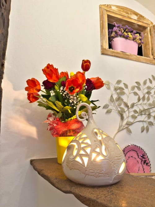 Vivaci tulipani rossi in vaso giallo con lanterna bianca decorativa presso Regnos Altos Boutique Rooms a Bosa, Italia