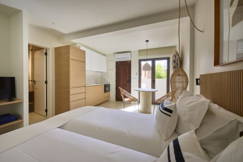 Estúdio Casa Redonda em Villas Aura em Aroeira com camas gêmeas, kitchenette, luminária de fibra trançada e vista para o jardim