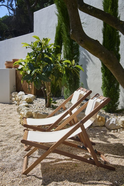 Two wooden deck chairs with white cushions in a sandy courtyard at Casa Redonda, Aroeira, Portugal