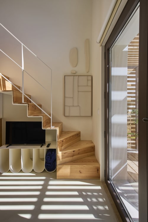 Modern duplex interior at Casa Redonda with wooden stairs, TV area, and glass doors opening to pool terrace in Aroeira