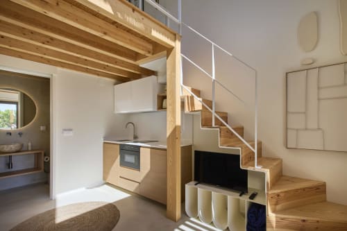 Modern duplex apartment interior at Casa Redonda, Aroeira with wooden stairs, open kitchen, and living area with TV