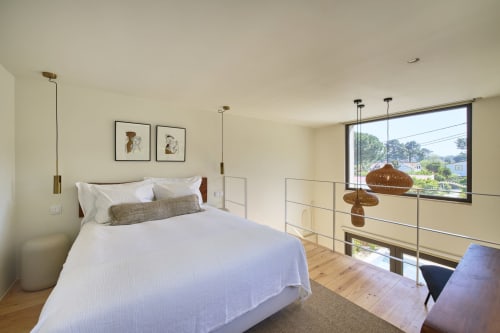 Modern bedroom in Casa Redonda duplex apartment, Aroeira Portugal, with bed, pendant lights, glass balcony railing and pool