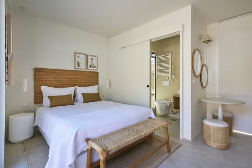 Bright bedroom at Casa Redonda villa in Aroeira with wooden bed, white linens, ensuite bathroom, and modern furnishings