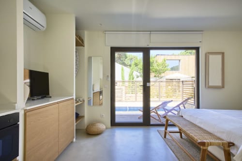 Modern bedroom at Casa Redonda, Aroeira with pool view, wooden furnishings, TV, and direct access to garden patio