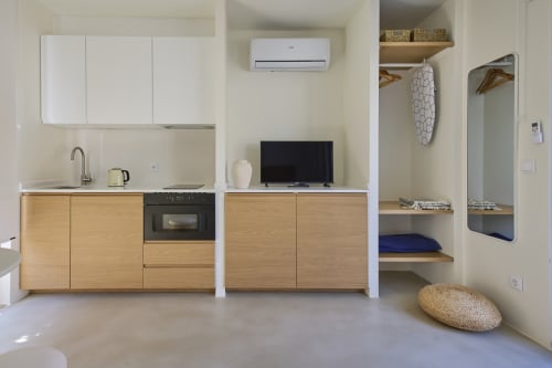 Modern kitchen and living area in Casa Redonda apartment at Aroeira with wooden cabinetry, TV, and pool view
