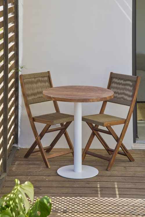 Mesa redonda de madeira com duas cadeiras trançadas no terraço de Casa Redonda, apartamento em Aroeira Portugal com vista para o jardim