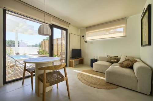 Apartamento moderno na Casa Redonda, Aroeira com sofá bege, mesa de jantar, TV e vista da piscina através de portas de vidro