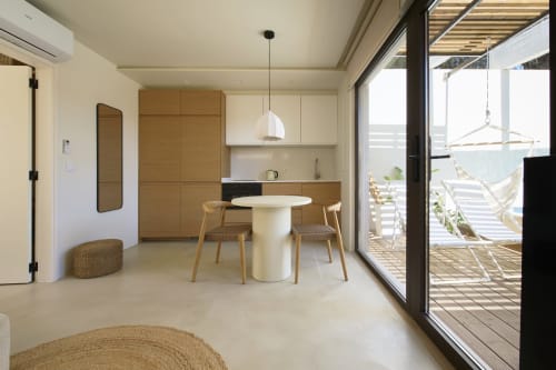 Cozinha e sala de jantar modernas com móveis em madeira, mesa redonda branca e vista para a piscina na Casa Redonda, Aroeira