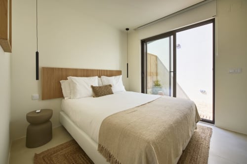 Quarto moderno na Casa Redonda Aroeira com cama queen, vista para jardim, cabeceira em madeira e acesso à piscina