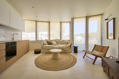 Bright open-plan apartment at Casa Redonda, Aroeira with modern kitchen, beige sofa, wooden chair, and round jute rug facing