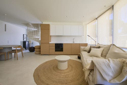 Modern open-plan apartment at Casa Redonda, Aroeira with beige sofa, wooden kitchen, round rug and garden views